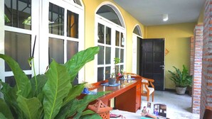 A room with a wooden bench, potted plants, and a table with books and a small figurine. - Kanti Kinasih Homestay by The Grand Java (Yogyakarta)