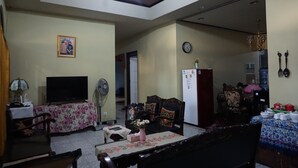 A living room with a television, sofa, and dining area. - Kanti Kinasih Homestay by The Grand Java (Yogyakarta)