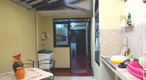 A narrow kitchen with a dining area, a window, and a tiled backsplash. - Kanti Kinasih Homestay by The Grand Java (Yogyakarta)