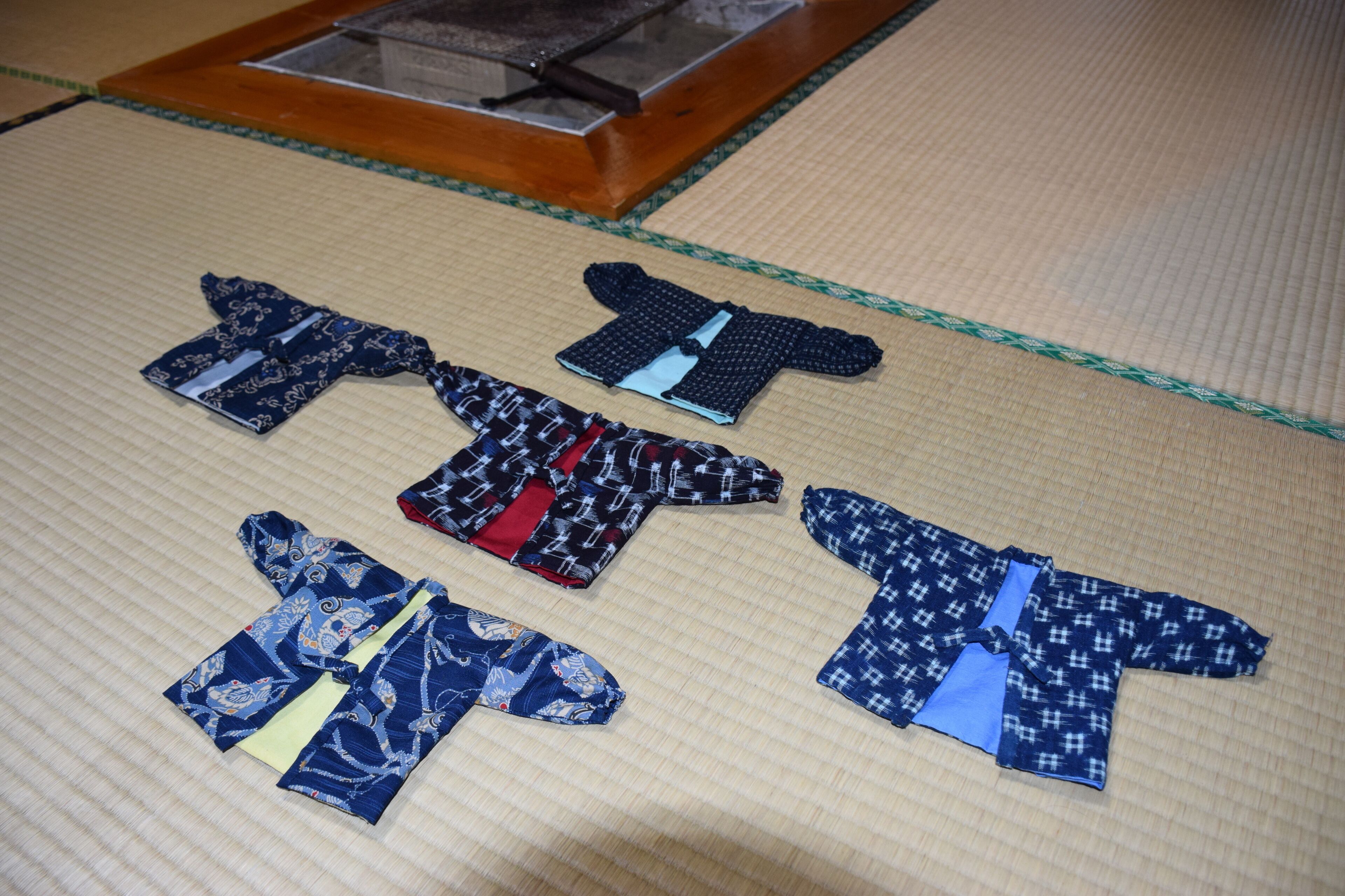 Ett golv täckt av tatamimattor, med fyra traditionella japanska kimonos utlagda på dem.