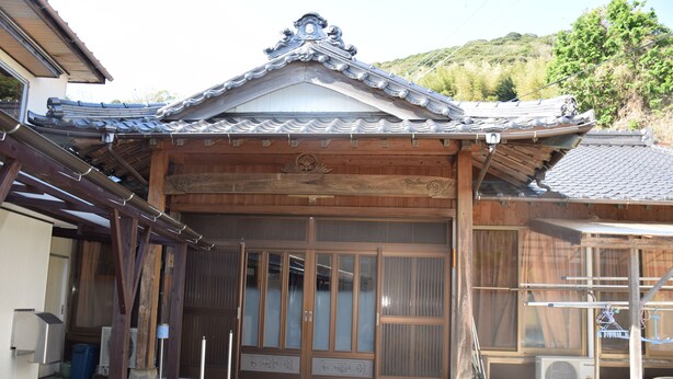 En traditionel japansk bygning med et flisegulvt tag, trædøre og en lille veranda.