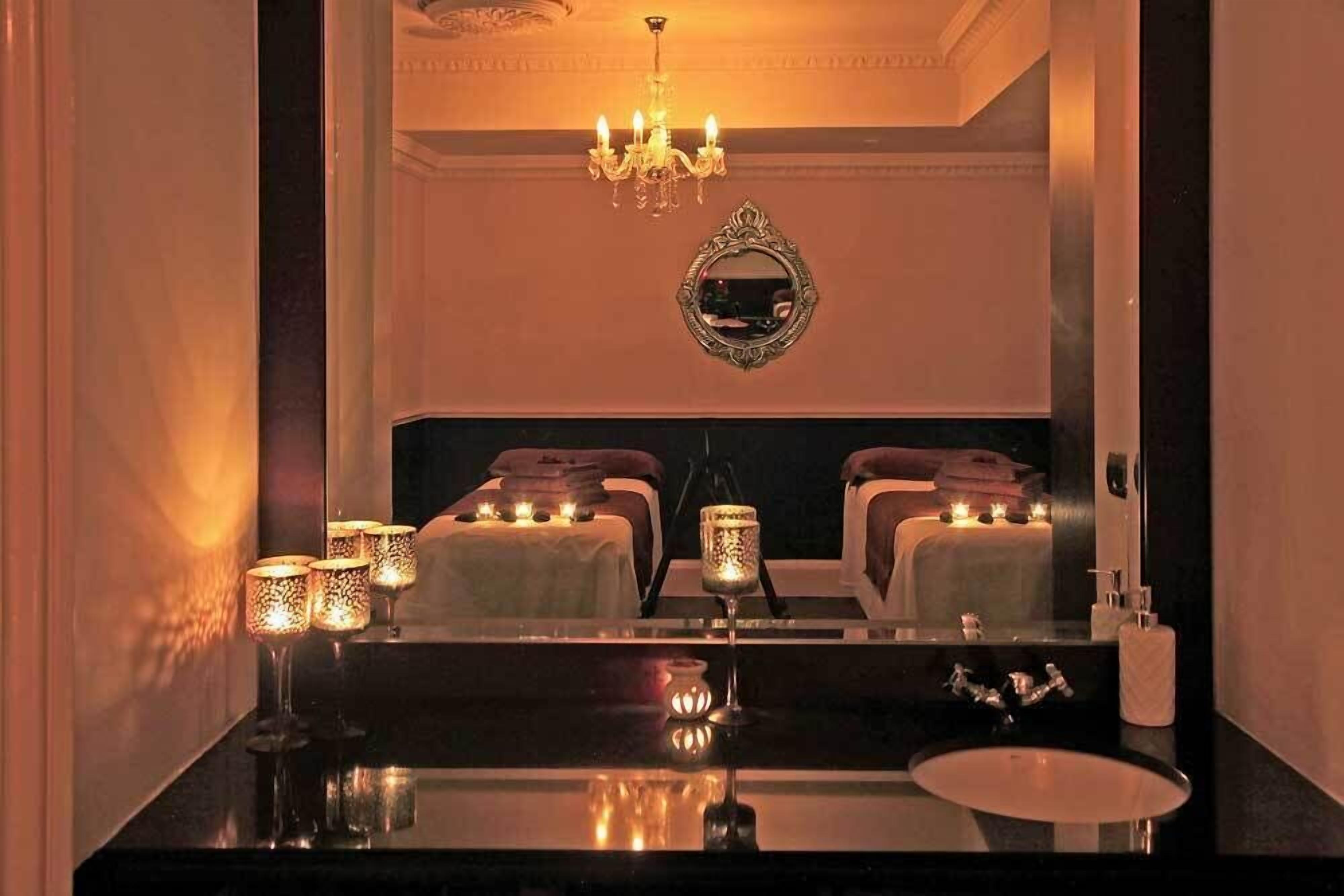A hotel bathroom with a large mirror, a chandelier, and candles on the vanity.