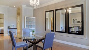 A dining area with a glass table, two chairs, and a chandelier. - Unit Number 204 Cape Royale Luxury Apartments (Cape Town)