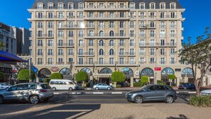 A multi-story hotel with a classic architectural style, featuring a central entrance with a canopy, multiple balconies, and a series of shops on the ground floor. - Unit Number 204 Cape Royale Luxury Apartments (Cape Town)