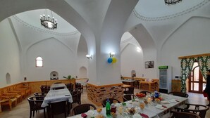Un comedor espacioso con techos altos de arco, mesas y sillas de madera.