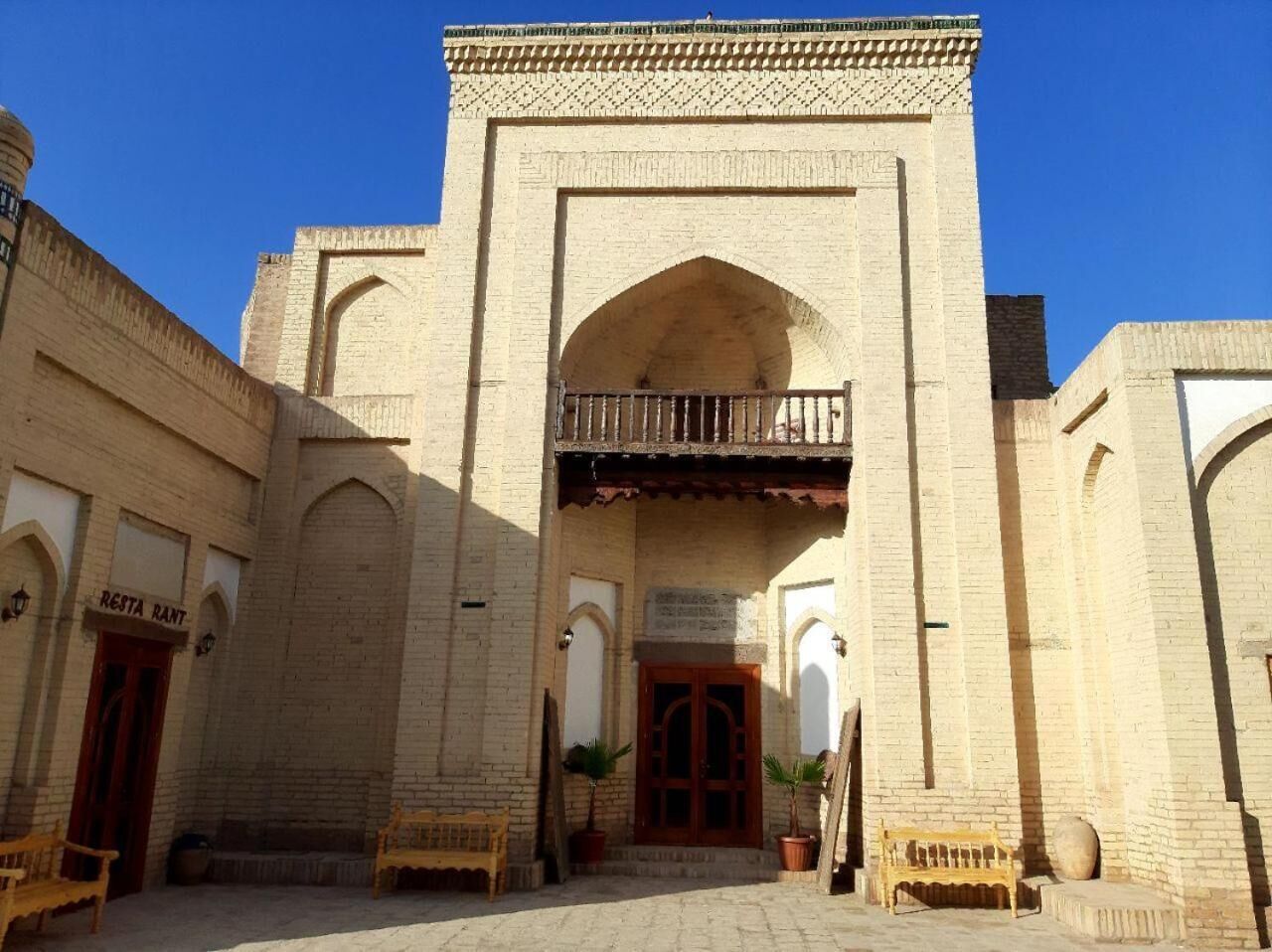 A traditional building with a central archway, a balcony, and a sign indicating a restaurant.