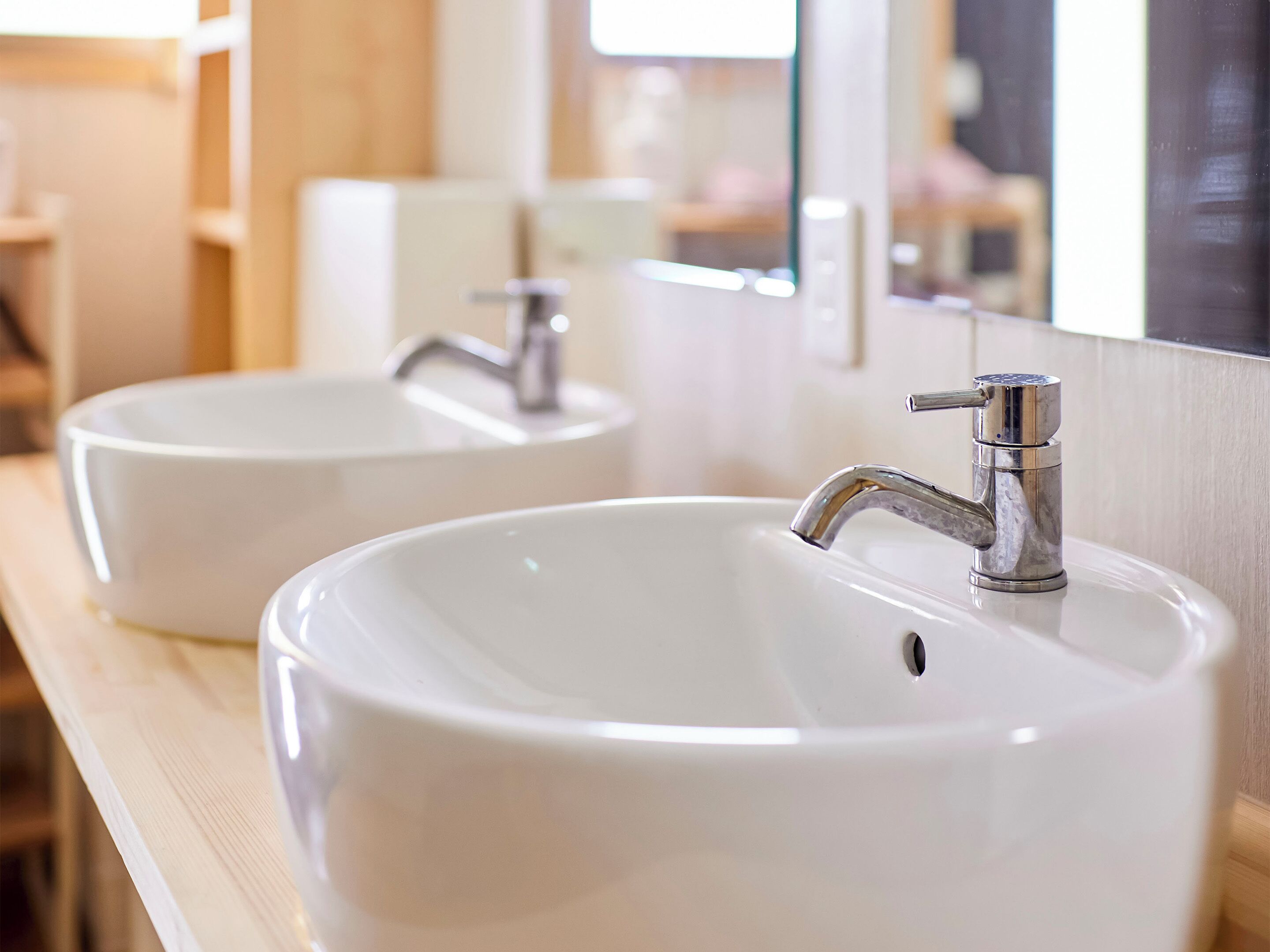 Deux éviers blancs, dotés de robinets modernes, sont installés sur un plan de travail en bois.