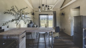 Cucina con isola centrale, sgabelli da bar, lampadario e vista attraverso una finestra.