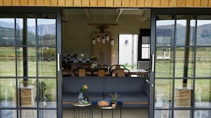 Un interno moderno con divano, tavolo da pranzo e sedie, ampie finestre con vista sull'esterno.