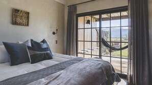 Una camera da letto con un letto grande, vista su un'amaca all'esterno e una finestra con tende.