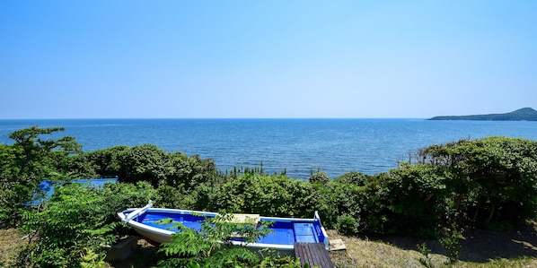 Un barco amarrado cerca de una zona verde exuberante, con vista al mar y una isla distante.