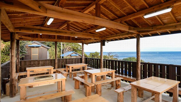 Une terrasse en bois avec des tables de pique-nique, donnant sur l’océan.