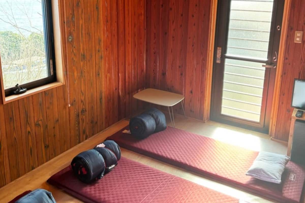 Ein Zimmer mit Holzwänden, einem Fernseher, zwei roten Matten und einem kleinen Tisch.