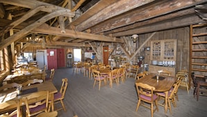 A rustic wooden dining area with high ceilings and exposed beams, featuring wooden tables and chairs. - Westerås Gard (Stranda)