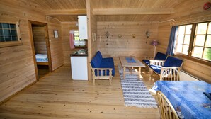 A wooden cabin interior with a dining area, sofa, and a kitchen. - Westerås Gard (Stranda)