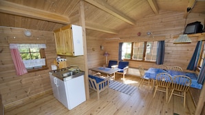 A wooden cabin interior with a kitchen, dining area, and a TV mounted on the wall. - Westerås Gard (Stranda)