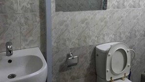Une salle de bain avec un lavabo, des toilettes et des murs carrelés.