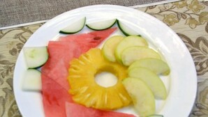 Une assiette contenant des tranches de pastèque, d’ananas et de pomme.