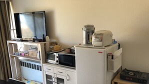 A compact kitchen with a microwave, toaster, and kettle on the counter, a refrigerator, and a small table with a chair. - Alpha Lodge Madarao (Myoko)