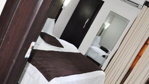 Habitación de hotel con dos camas, un espejo grande y un armario.