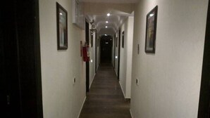 Un pasillo estrecho y tenuemente iluminado con cuadros en las paredes, que conduce a un final oscuro.
