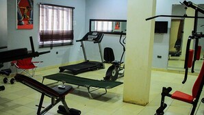 Ein Fitnessraum mit Trainingsgeräten, darunter Laufbänder, eine Hantelbank und ein Squat-Gestell.
