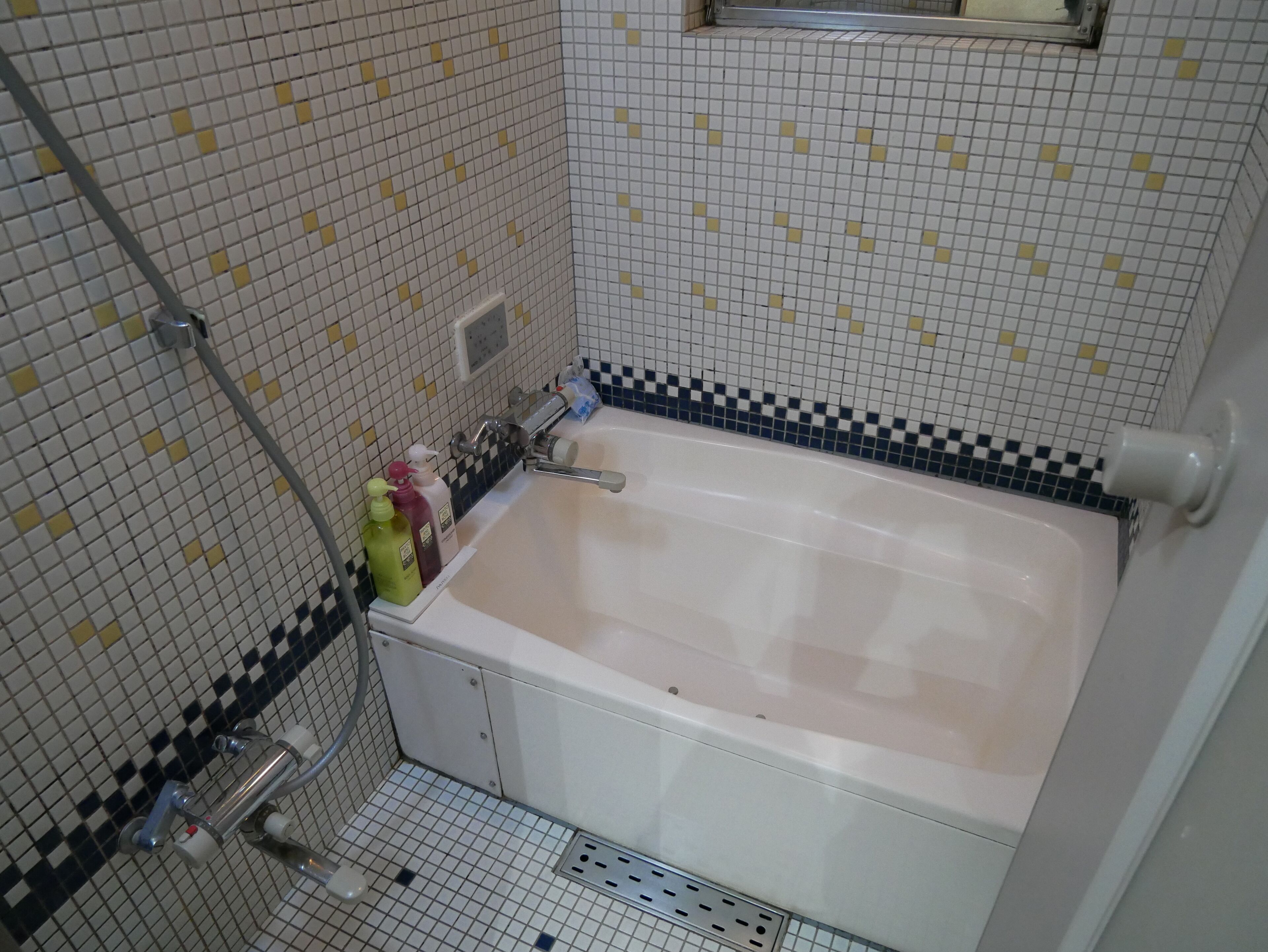 Ein Badezimmer mit Badewanne, Dusche und Toilette. Auf dem Waschbecken liegen Pflegeprodukte.