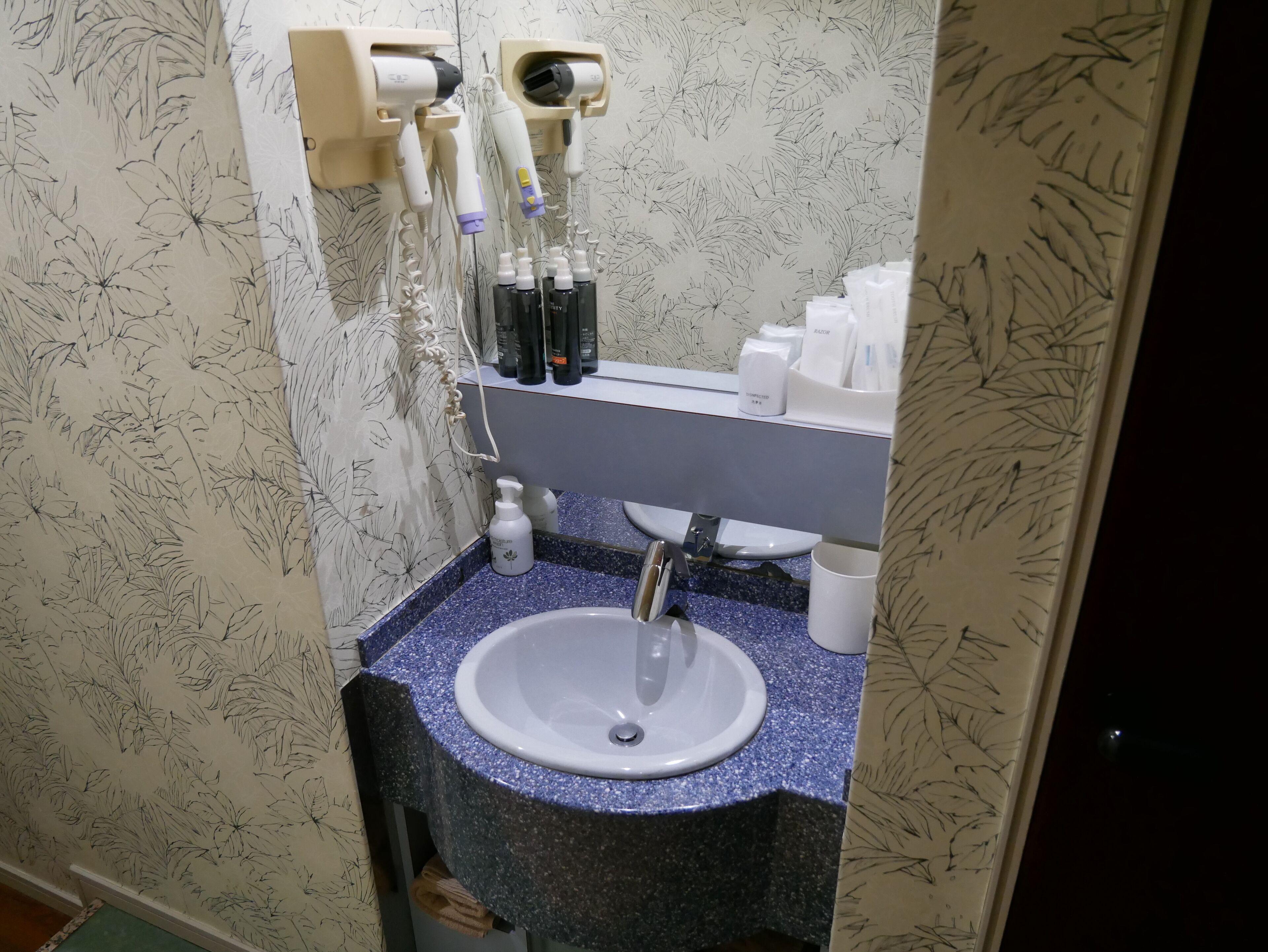 Un baño con lavamanos, secador de pelo y distintos artículos de aseo.