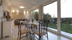 A modern kitchen with a dining area, large windows, and a stone wall.