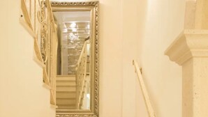 A staircase with a mirror on the wall, leading to a landing with a light fixture.