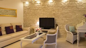 A living room with a stone wall, a sofa, a television, a coffee table, and a wicker chair.