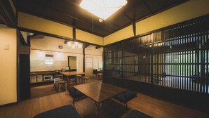 Ein traditioneller japanischer Raum mit Tatami-Boden, einem niedrigen Tisch mit Kissen und einer Schiebetür mit Gittermuster.