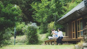 Eine Holzhütte mit Veranda, umgeben von dichtem Wald.