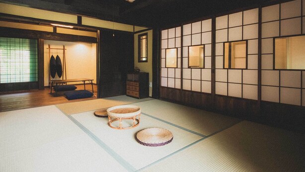 Ein traditioneller japanischer Raum mit Tatami-Böden, einem niedrigen Tisch und einer hängenden Leuchte.