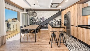 Una cocina moderna con una isla de madera, taburetes de bar y vistas a la ciudad a través del ventanal.