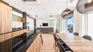 Una cocina moderna con encimera negra, armarios de madera y una mesa de comedor grande con sillas.