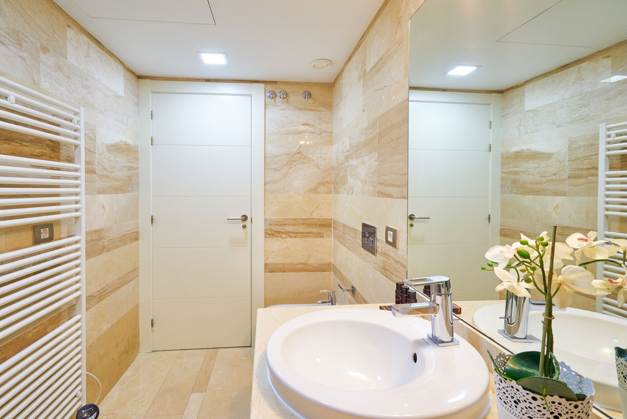Une salle de bain moderne avec un grand lavabo blanc, un miroir et un porte-serviettes.
