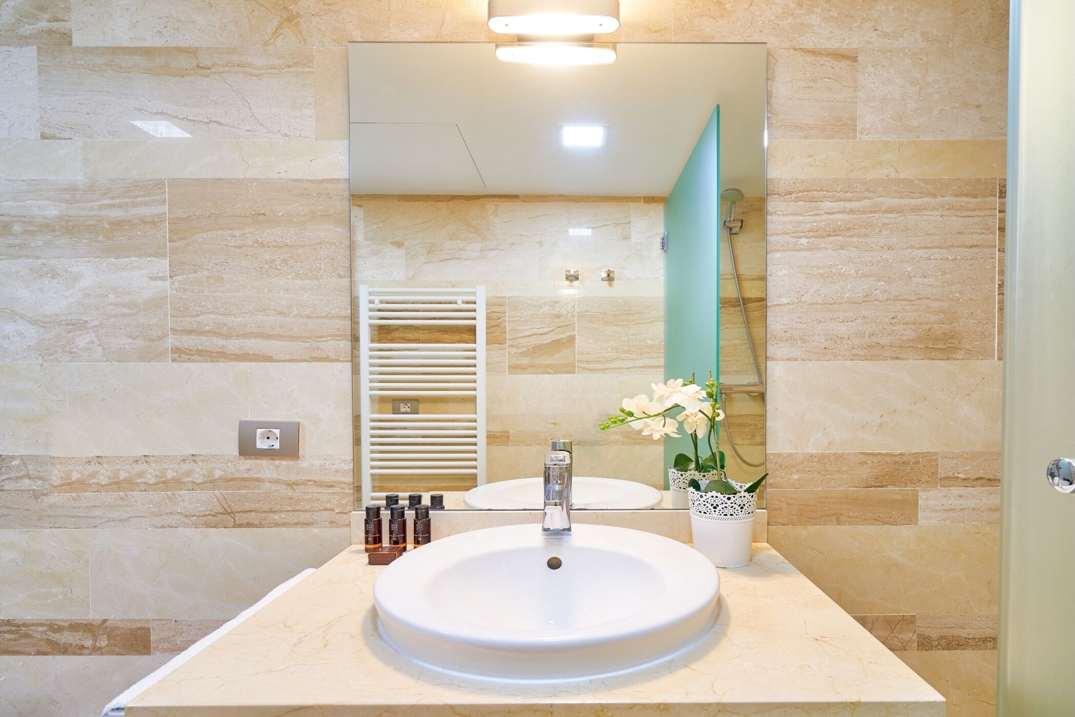 A bathroom with a large mirror, a sink, and a shower.