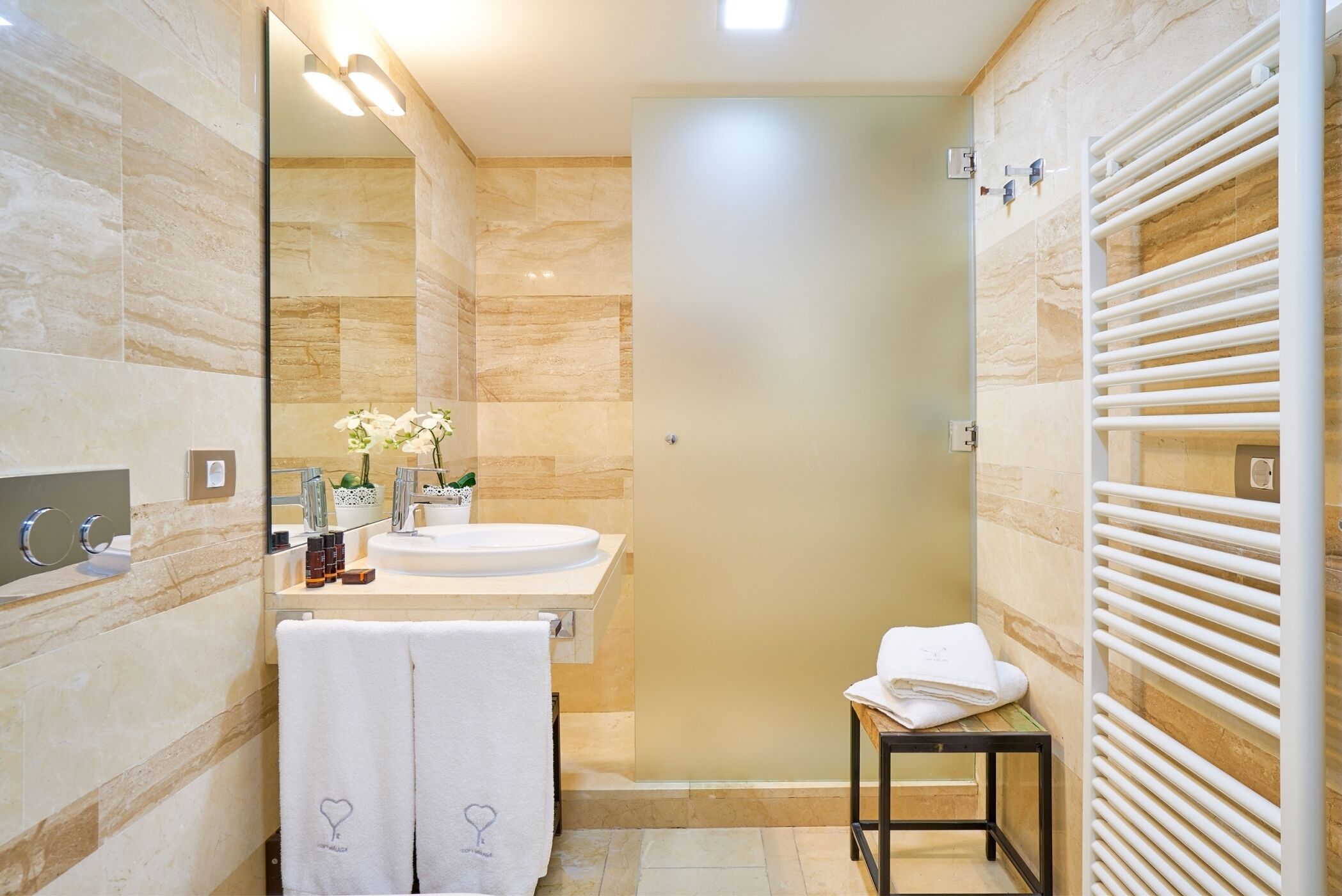 Une salle de bain moderne avec un grand miroir, un lavabo, un porte-serviettes et un espace douche.