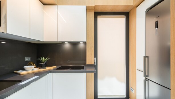 A modern kitchen with white cabinets, a black countertop, a stainless steel refrigerator, and a small potted plant on the counter. - iloftmalaga Cisneros IV (Málaga)