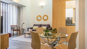 A modern living room with a glass dining table, wicker chairs, a grey sofa, and a large window with curtains. - iloftmalaga Cisneros IV (Málaga)