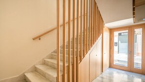A staircase with wooden railings and marble steps leading to a door with glass panels. - iloftmalaga Cisneros IV (Málaga)