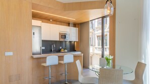 Une cuisine moderne dotée d’un îlot central, de tabourets de bar et d’une table à manger en verre avec des chaises.