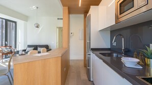 Une cuisine moderne dotée d’un îlot central, d’appareils électroménagers en acier inoxydable et d’un plan de travail foncé.
