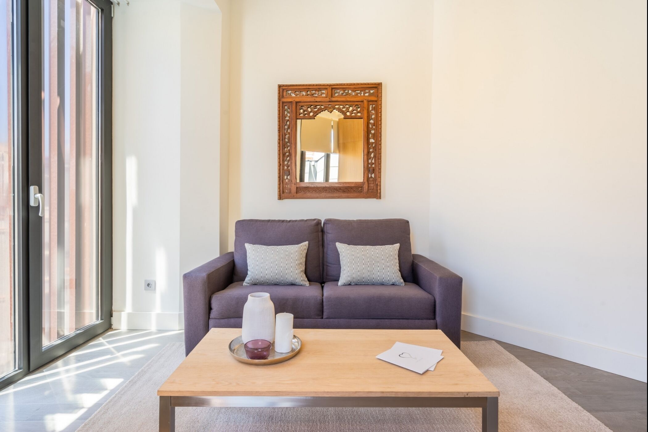 A modern living room with a sofa, a coffee table, and a decorative mirror.