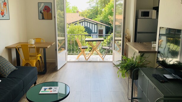 A modern living room with a balcony, a dining area, and a kitchen area. - "L'Etale", apartment with terrace in the heart of the city center. 2 steps from the lake (Soorts-Hossegor)