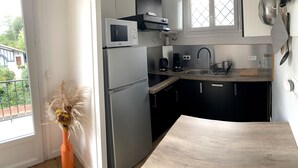 A compact kitchen with a refrigerator, microwave, and sink. - "L'Etale", apartment with terrace in the heart of the city center. 2 steps from the lake (Soorts-Hossegor)