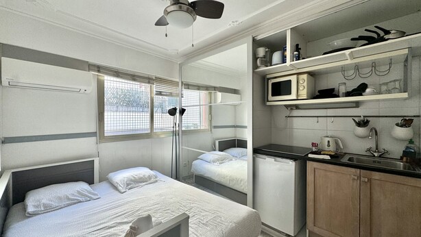 A compact hotel room with a single bed, a small kitchenette, and a window with blinds. - Minerve 1,6 minuts walk from Palais (Cannes)