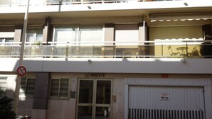 A building with a ground-level entrance labeled "LE MINERVE," a closed garage door, and a balcony with outdoor seating. - Minerve 1,6 minuts walk from Palais (Cannes)