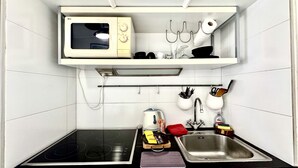 A compact kitchen with a microwave, kettle, kettle pot, and a sink. - Minerve 1,6 minuts walk from Palais (Cannes)